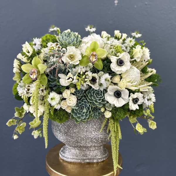 White and green floral arrangement in a silver urn vase