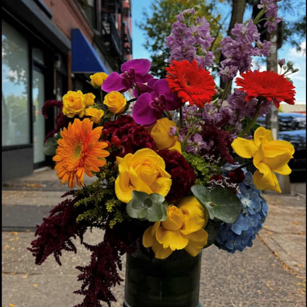 Colorful bouquet with roses, orchids, gerbera daisies, and hydrangea in a dark vase