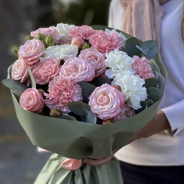 Bouquet of pink roses and white carnations wrapped in green paper