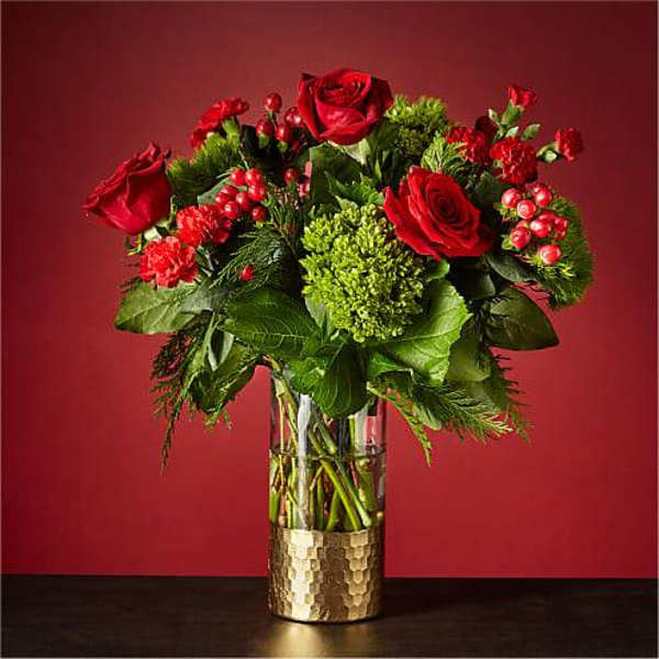 Red roses and carnations in a clear glass vase with green filler