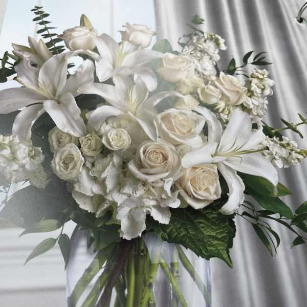 White lilies and cream roses in a bouquet with greenery