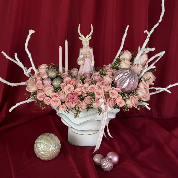 Pink rose arrangement in a white vase with candles and decorative ornaments