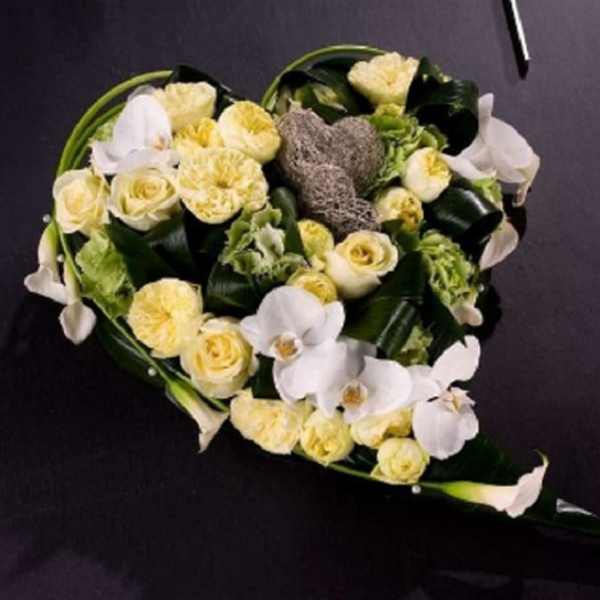 Heart-shaped bouquet of white and pale yellow flowers on a dark background