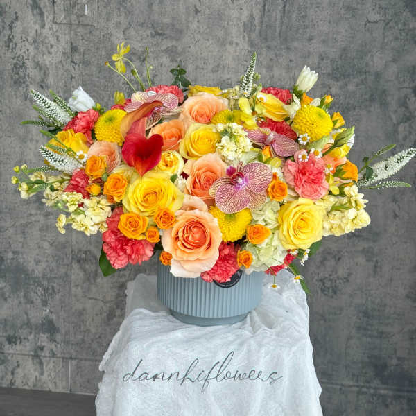 Large mixed bouquet in a ribbed blue vase with yellow, peach, pink, and white blooms