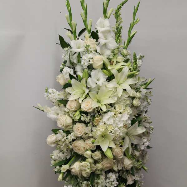Tall white standing spray with lilies and roses on a metal easel