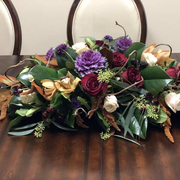 Low floral centerpiece with red, white, and purple blooms on a dining table