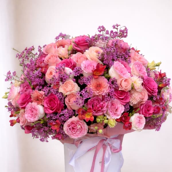 Large pink and purple rose bouquet in a white hat box with ribbon