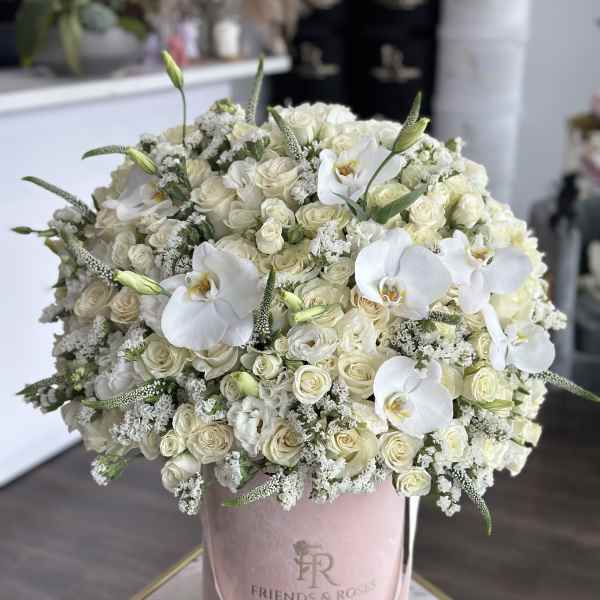 Large white rose and orchid arrangement in a pink hatbox