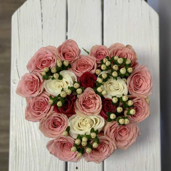 Heart-shaped bouquet of pink and white roses with berry accents