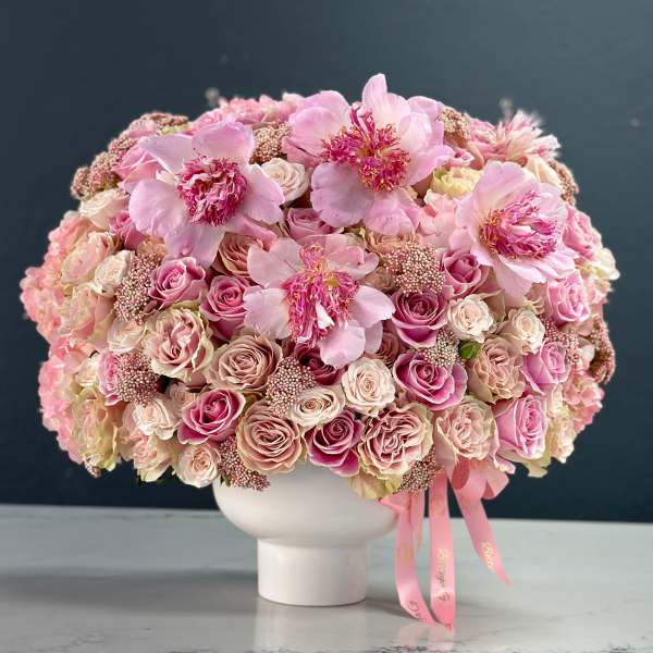Pink rose bouquet in a white vase with ribbon