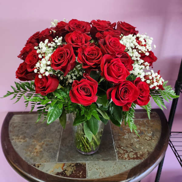 Red roses and white baby's breath arranged in a clear glass vase