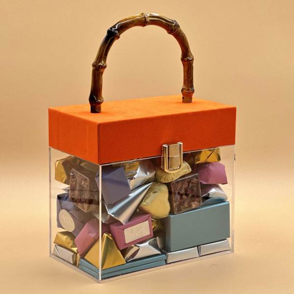 Clear gift box with assorted chocolates and an orange lid with handle