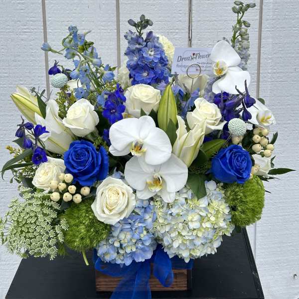 Blue and white floral arrangement with roses, orchids, lilies, and hydrangeas