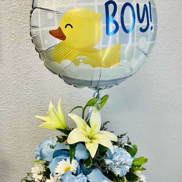 Duck-shaped balloon above a blue and white flower arrangement