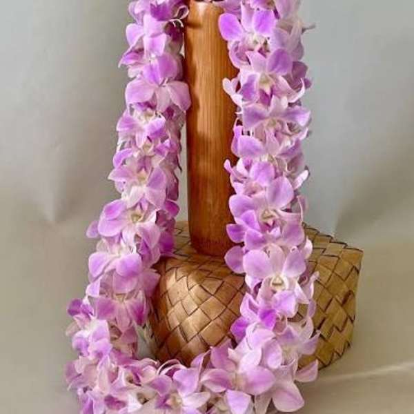 Purple orchid lei draped over a carved wooden vase