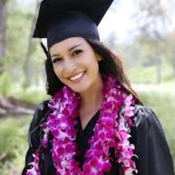 Graduate in cap and gown wearing a pink flower lei