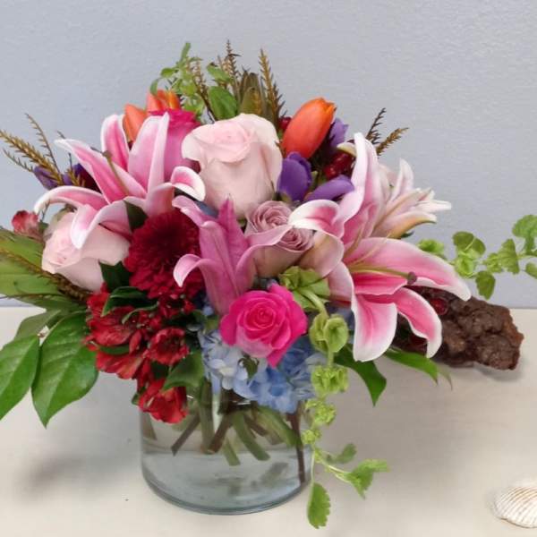 Pink lilies and roses arranged in a glass vase