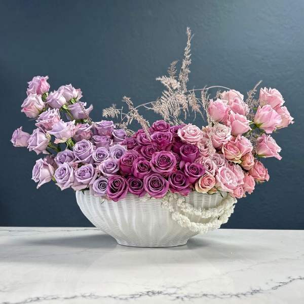 Pink and lavender roses arranged in a white vase