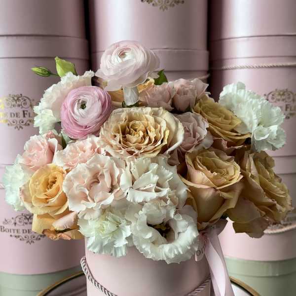 Pastel roses and carnations arranged in a pink hat box
