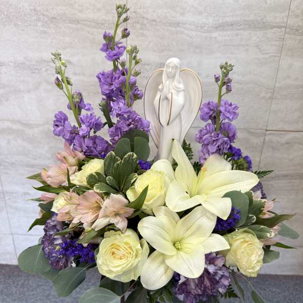 Purple and cream floral arrangement with a white angel figurine