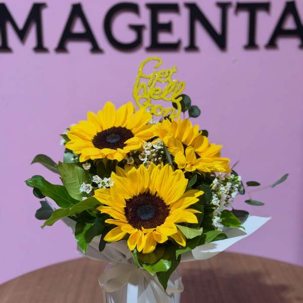 Bouquet of yellow sunflowers in a white wrapped vase