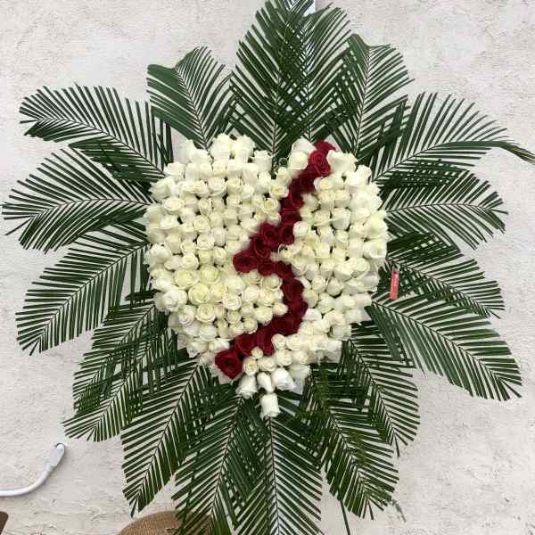 Heart-shaped rose wreath with white and red roses on a stand