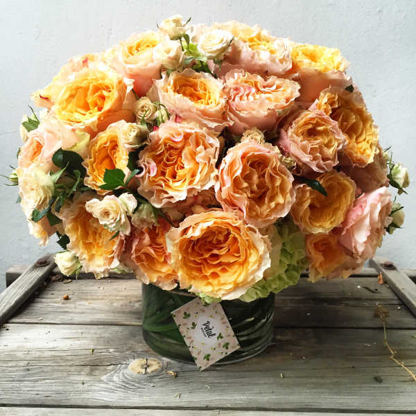 Bouquet of peach and yellow roses in a green vase