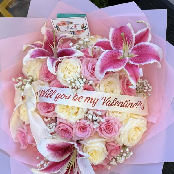 Heart-shaped bouquet of pink and cream roses with lilies and a Valentine ribbon