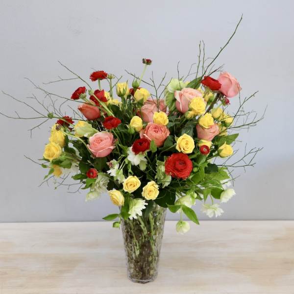 Mixed roses and small white flowers in a clear glass vase