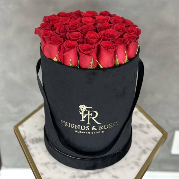 Red roses arranged in a black round hat box