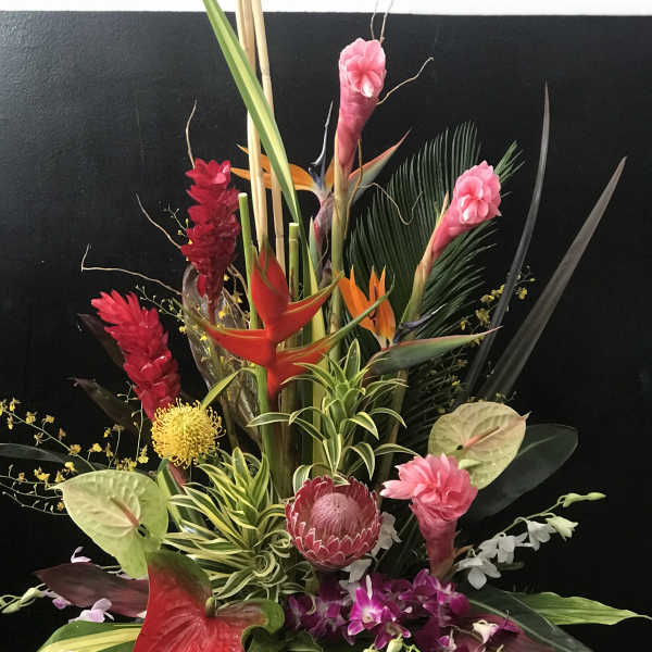 Tropical floral arrangement with pink ginger, red anthuriums, and orchids