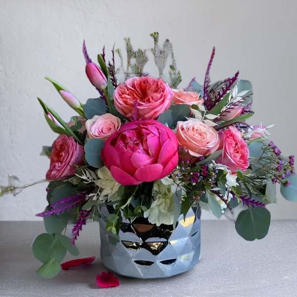 Pink floral arrangement in a reflective silver vase