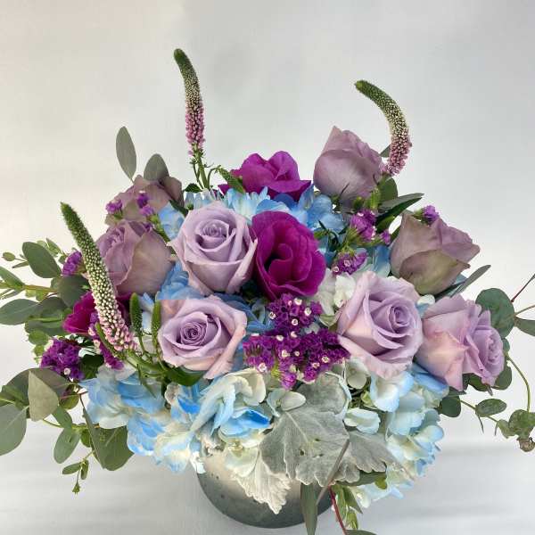Lavender roses and blue hydrangeas in a low vase arrangement