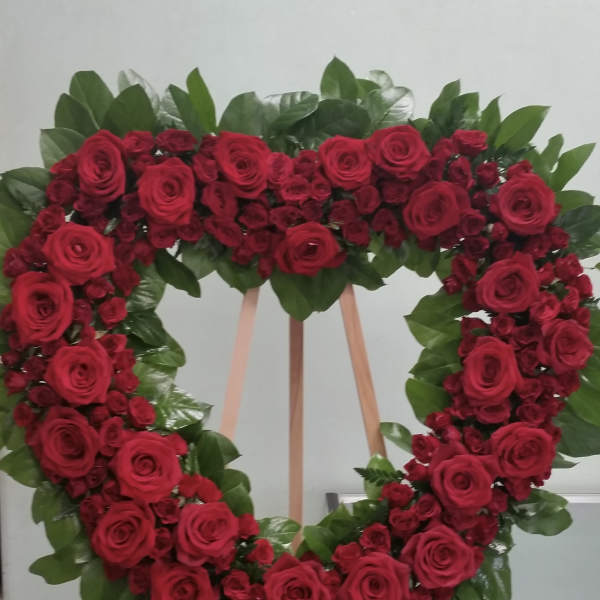 Heart-shaped wreath of red roses on a wooden easel