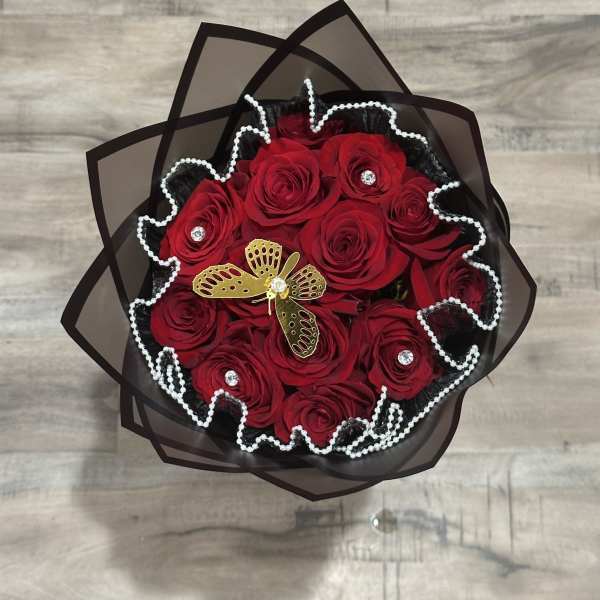Bouquet of red roses wrapped in black paper with pearl trim