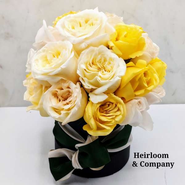 Bouquet of cream and yellow roses in a black hat box with ribbon