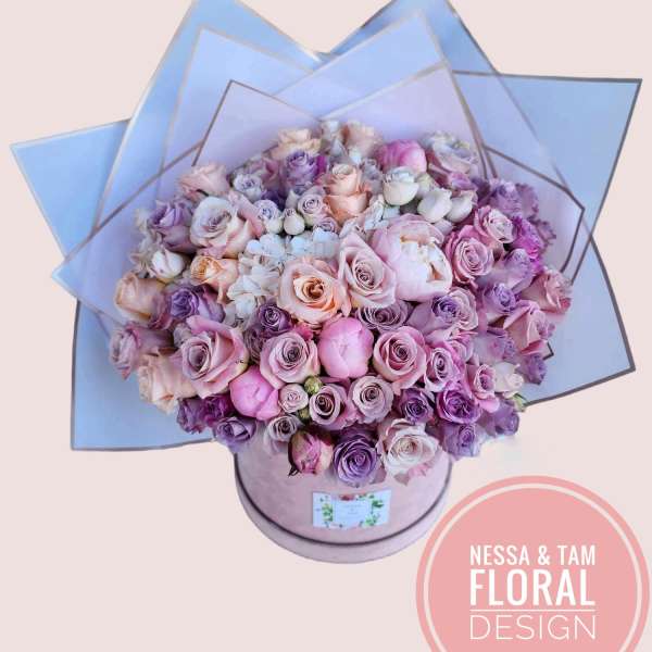 Large bouquet of pink and lavender roses in a round box