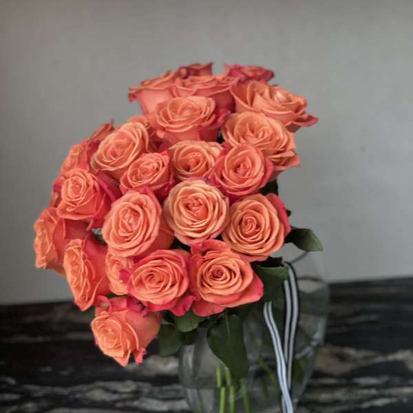 Bouquet of coral and pink roses in a clear glass vase