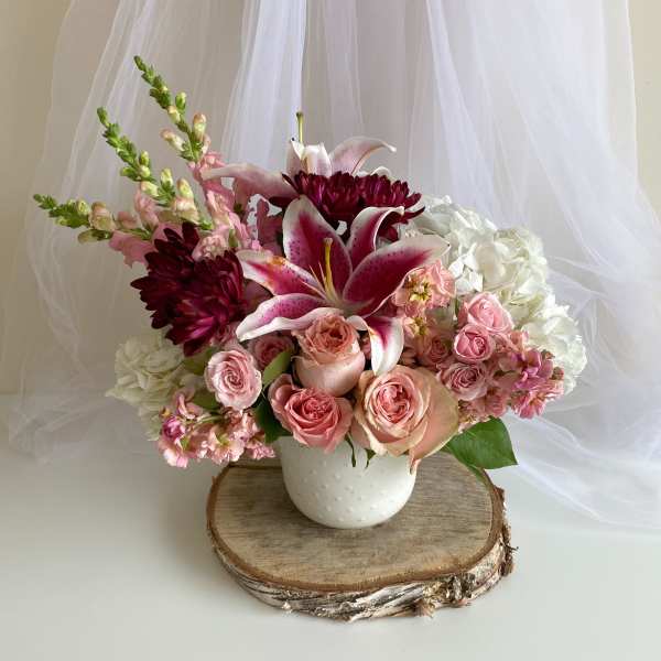 Pink and white floral arrangement in a white vase with lilies and roses