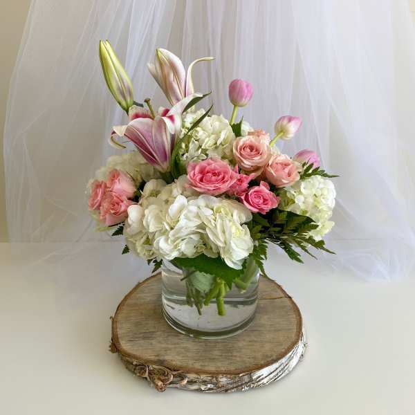 Pink roses and white hydrangeas in a glass vase with lilies and tulips