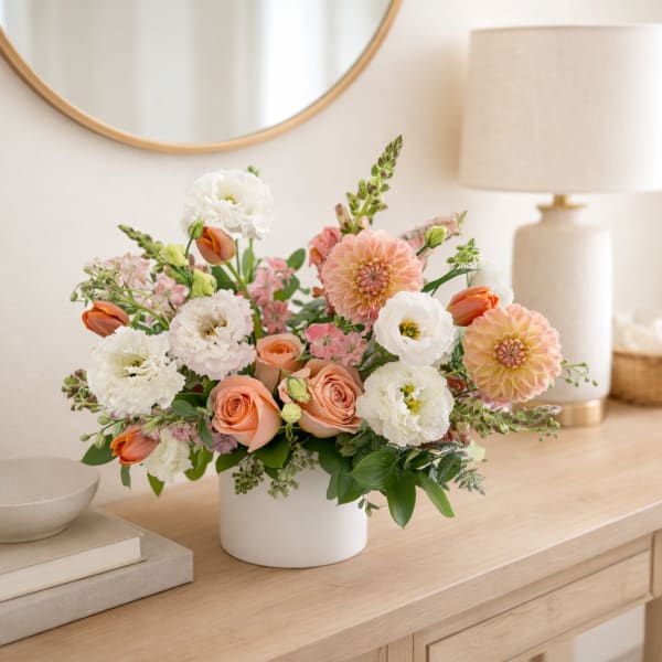 Peach roses and white blooms arranged in a white vase