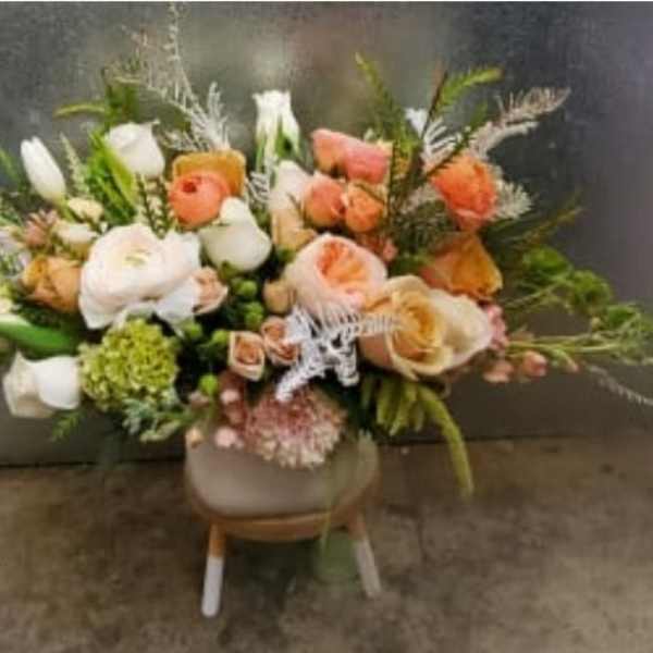 Mixed bouquet of peach, white, and coral flowers in a vase