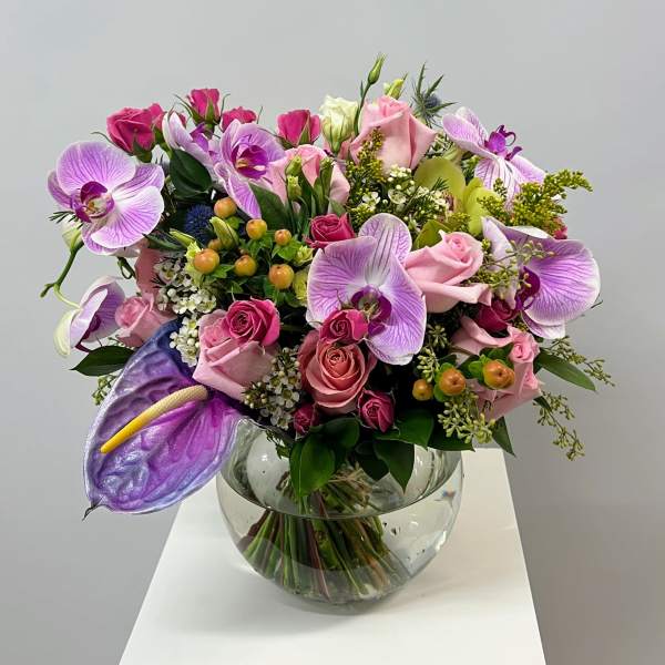 Pink and lavender bouquet with roses and orchids in a glass vase