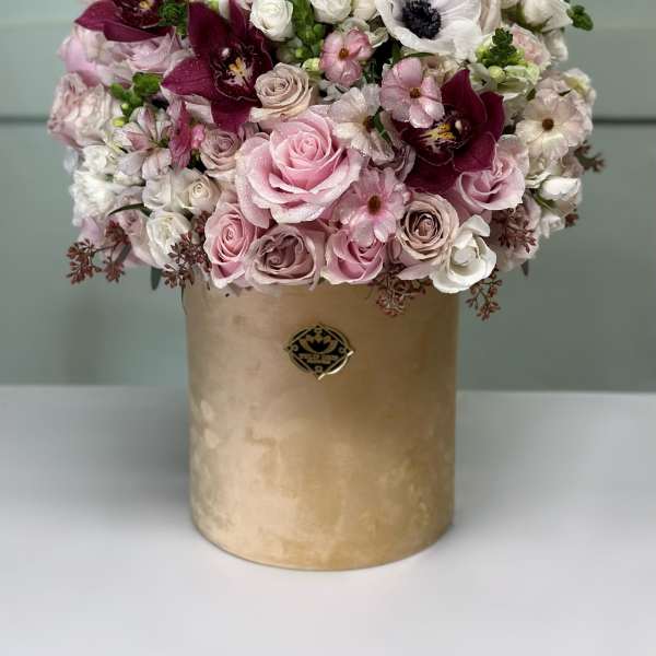 Pink and white bouquet in a gold cylindrical box