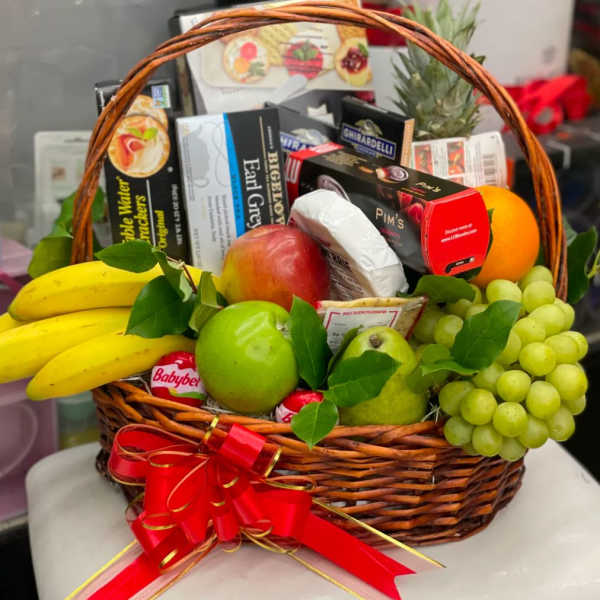 Gift basket with fruit and assorted snack boxes tied with a red ribbon