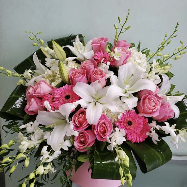 Pink roses and white lilies with gerbera daisies in a pink box