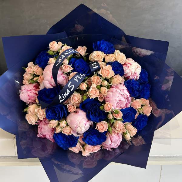 Bouquet of blue and blush roses wrapped in dark blue paper