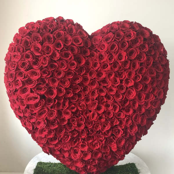 Heart-shaped arrangement of red roses on a white stand