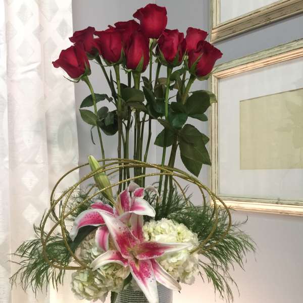 Tall vase arrangement with red roses, pink lilies, and white hydrangeas