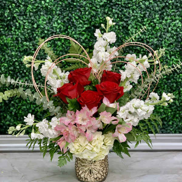 Red roses and pink-white flowers in a decorative vase